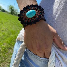 "Brown leather bracelet that has a paisley filigree. It is adorned with turquoise cabochon concho and a hand painted leather rosette. Measures 7.75\" to 8.25\" with two snaps for adjustment." Western Style Turquoise Leather Bracelets, Western Style Turquoise Bracelet, Hand Tooled, Turquoise Leather Concho Bracelets, Adjustable Turquoise Leather Bracelet With Concho, Vintage Turquoise Hand-tooled Bracelets, Vintage Turquoise Bracelets With Hand Tooling, Adjustable Turquoise Cuff Bracelet With Concho, Vintage Turquoise Leather Jewelry, Turquoise Leather Concho Jewelry