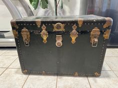 an old black suitcase sitting on the floor in front of a washer and dryer