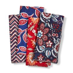 four napkins in different colors and patterns on a white background, each with a flower design