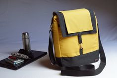 a yellow and black backpack sitting next to a laptop computer on top of a table