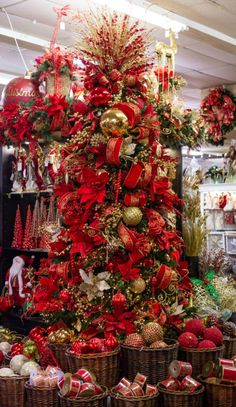 a christmas tree is decorated with red and gold ornaments, including balls, tinsels and bows