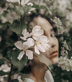 a woman with flowers in her hair is looking at the camera while she's surrounded by trees