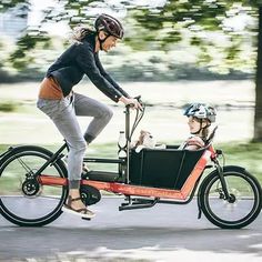 a woman riding on the back of a bike with a small child in the sidecar