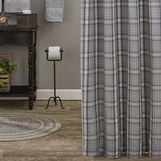 a bathroom with a shower curtain, rug and toilet paper dispenser on the floor