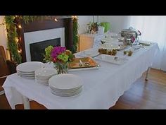 the table is set with many plates and silverware on it, along with a fireplace