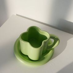 two green cups and saucers on a white surface