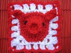 a red and white crocheted square with a pig on it