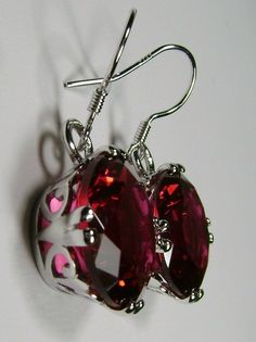 <> This is a brand new beautiful Art Nouveau inspired filigree sterling silver pair of fleur de lis style dangle drop earrings. The round full cut 20ctw Simulated/man-made red rubies gemstones are 15mm (9/16th of an inch) in diameter. The earrings are 1 5/16th inches long.. Notice the beautiful fleur de lis filigree settings. This is a well made beautiful pair of earrings and they are ready to wear. The color and clarity of the red ruby stones is simply stunning. A gift box is included for Red Oval Earrings For Formal Occasions, Formal Red Oval Earrings, Classic Red Ruby Earrings, Classic Ruby Red Earrings, Red Pierced Earrings For Formal Occasions, Red Formal Pierced Earrings, Formal Red Pierced Earrings, Red Pierced Earrings For Anniversary, Red Oval Ruby Earrings