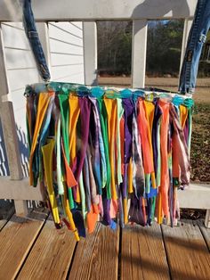 colorful ribbons hang from the back of a wooden porch rail on a deck in front of a white house