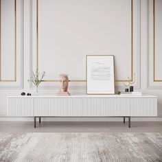 a white and gold living room with an art piece on the table next to it