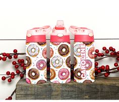 three donuts and sprinkles are on the top of two water bottles