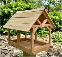 a wooden bird house sitting on top of a rock covered ground