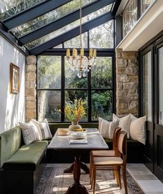 a room with a table, couches and chandelier hanging from the ceiling