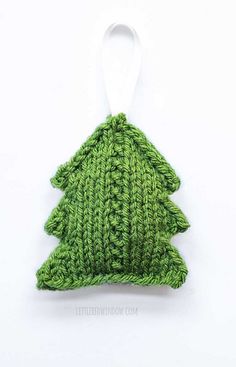 a green knitted christmas tree ornament hanging from a white string on a white background