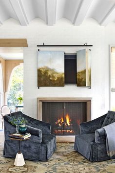 a living room with two chairs and a fire place in the middle of the room