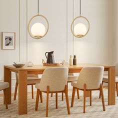 a dining room table with four chairs and two pendant lights hanging from the ceiling above it