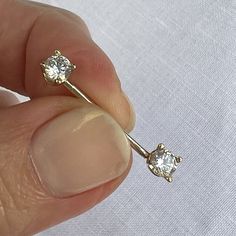 a person holding a pair of diamond studs in their left hand and the other hand