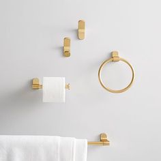 gold bathroom accessories on white wall with towel ring and napkin holder in the corner, closeup