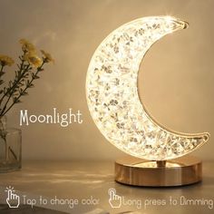 the moon lamp is sitting next to a vase with flowers