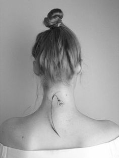 the back of a woman's neck with an arrow tattoo on her left side