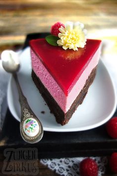 a piece of cake on a white plate with raspberry sauce and flower decoration