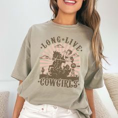 Yeehaw, Cowgirl! Ready to celebrate the spirit of the West with style and flair? Lasso up the "Long Live Cowgirls" Comfort Color Tee – the perfect tribute to the fearless and fabulous women of the rodeo. Crafted from premium Comfort Color fabric, this tee offers unbeatable comfort and durability, perfect for all your Western adventures. The bold design proudly proclaims "Long Live Cowgirls," honoring the strength, independence, and spirit of the women who ride with the wind. Whether you're breaking in a new bronco or two-stepping under the stars, this tee is your go-to choice for casual comfort and Western charm. Its relaxed fit ensures you stay cool and carefree, whether you're roping cattle or enjoying a well-deserved break at the saloon. From early morning trail rides to late-night barn Summer Graphic Tee For Western-themed Events, Graphic Tee For Western-themed Spring Events, Spring Graphic Tee For Western-themed Events, Retro Summer Tops For Western-themed Events, Retro Tops For Western-themed Summer Events, Crew Neck T-shirt For Western-themed Spring Events, Retro Crew Neck Tops For Western-themed Events, Graphic Print Crew Neck Tops For Western-themed Events, Crew Neck Top With Graphic Print For Western-themed Events