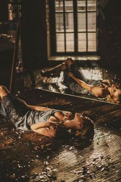 two women laying on the floor in an abandoned room with mirrors reflecting their bodies and hair