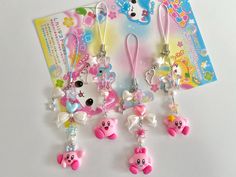 a group of cute little charms hanging from strings on a white surface with an advertise card in the background