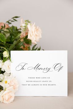 a bouquet of flowers sitting on top of a table next to a card with the words in memory of