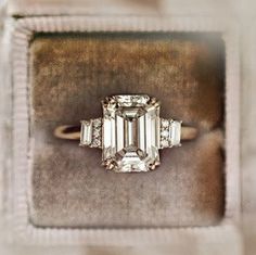 an emerald - cut diamond ring sits in a velvet box