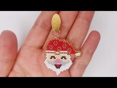 a hand holding a small beaded keychain with a santa clause on it