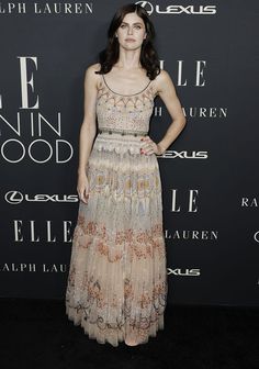 a woman in a dress standing on a black carpet