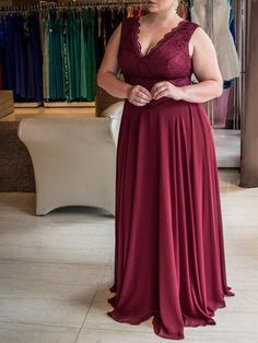 a woman in a red dress looking at her cell phone while standing in front of a rack of dresses