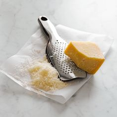 a grater and cheese are on a white napkin next to some grated cheese