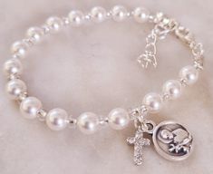 Celebrate the baptism of a baby girl with this beautiful white Swarovski pearls size 5. Bracelet length 14cm Extension 2.5cm. Brass and diamonties cross. please refer to drop down menu to choose your charm 1- Devine Jesus  2-Saint Girad Custom orders are available, please contact me to discuss anything you have in mind. Keep in mind a matching rosary is available on your request. Made in Australia, pearls are genuine Swarovski made in Austria. Please make sure to store item in packaging when not Classic Adjustable White Charm Bracelet, White Hypoallergenic Name Bracelet For Anniversary, Classic White Adjustable Charm Bracelet, Hypoallergenic White Name Bracelet For Anniversary, Adjustable Silver Pearl Bracelet For Baptism, Classic White Charm Bracelet As Gift, Classic White Charm Bracelet Gift, Elegant Silver Pearl Bracelet For Baptism, Classic Adjustable Jewelry For First Communion