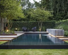 an outdoor swimming pool surrounded by grass and trees