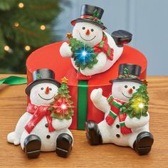 two snowmen sitting next to each other in front of a christmas tree