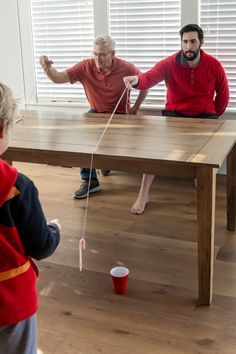 two adults and a child playing with toys on the floor in front of a table