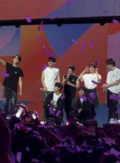 group of young men standing on stage with confetti flying in the air behind them