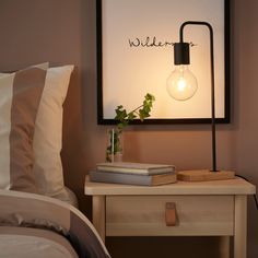 a lamp that is on top of a table next to a book and some pillows