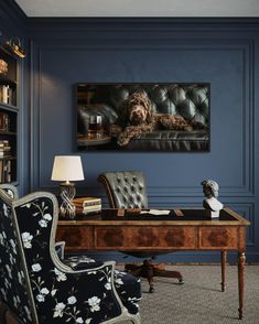 a dog laying on top of a leather chair in front of a desk with a lamp