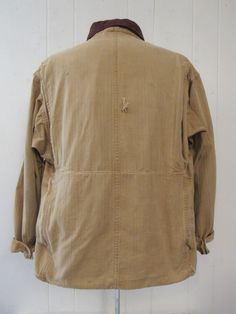 "Vintage 1930s or 40s hunting jacket. Made of khaki color herringbone twill cotton. Has a salt and pepper brown corduroy collar, tan corduroy cuffs, button front, five pockets, two shotgun shell pockets and a large back game pouch. Label reads: BLUE BILL BY THE MAKERS OF \"RED HEAD\". Size large. Actual measurements are: 46\" at the chest 48\" at the waist 21\" shoulder seam to shoulder seam 23\" shoulder seam to end of cuff 29.5\" overall length In very good condition with a 1\" hole at back an Vintage Brown Utility Jacket With Corduroy Collar, Vintage Beige Utility Jacket With Pockets, Vintage Beige Cotton Utility Jacket, Cotton Sport Coat For Hunting, Vintage Beige Cotton Outerwear, Vintage Long Sleeve Utility Jacket For Hunting, Vintage Brown Cotton Utility Jacket, Vintage Long Sleeve Sport Coat For Hunting, Vintage Cotton Hunting Outerwear