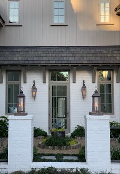 a white house with two lamps on the front door and windows in the side wall