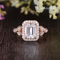 an engagement ring with a large diamond surrounded by smaller diamonds on a black table next to flowers