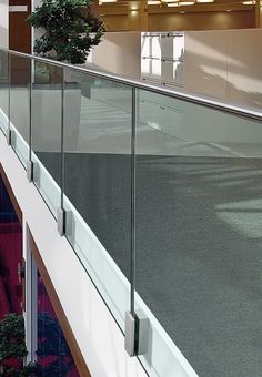 an office building with glass balconies and plants on the top floor, along with red carpeted stairs