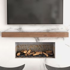 a flat screen tv mounted on the wall above a fireplace with logs in front of it