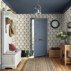 a blue door in a room with wallpaper and rugs on the wooden floor