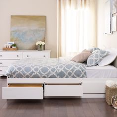 a white bed sitting in a bedroom on top of a hard wood floor next to a window