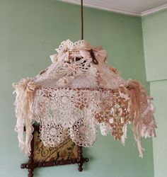 an old fashioned lamp hanging from the ceiling in a room with green walls and white lace