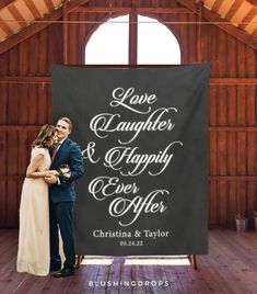 a couple standing next to each other in front of a black banner that says love laughter and happily ever after